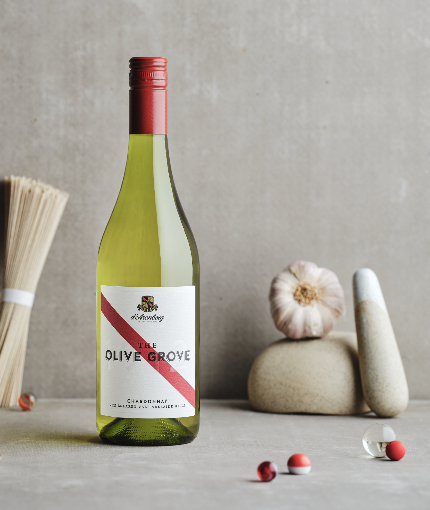 A bottle of The Olive Grove Chardonnay wine by d’Arenberg, featuring a wine label with a red stripe sitting on a table