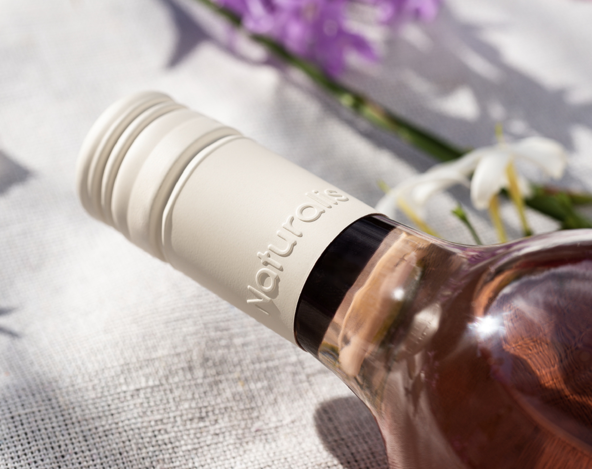 Close up of Angove's Naturalis wine Packaging matte, cream coloured screw-cap capsule with blind emboss logo. 
