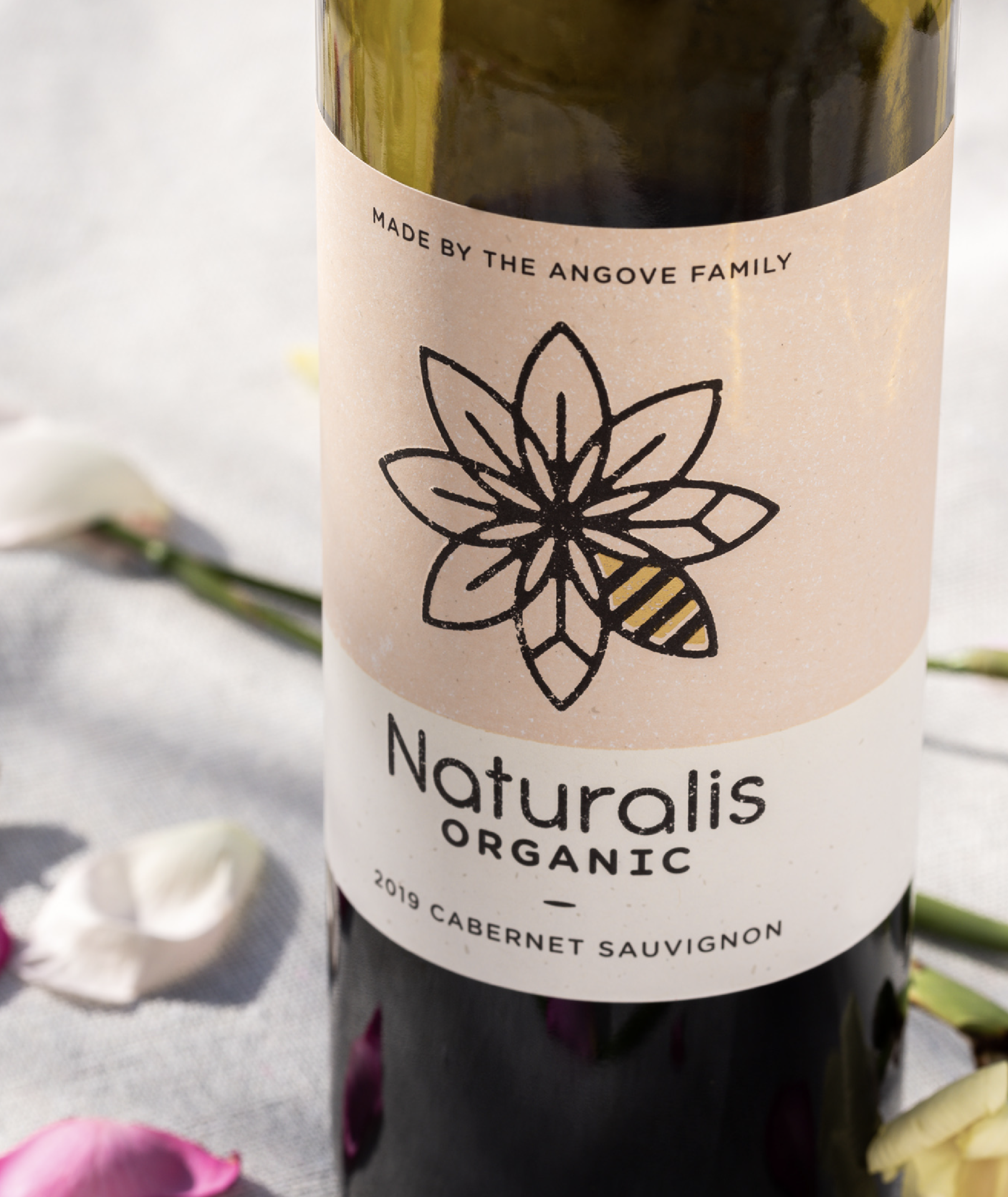 Close up of Angove's Naturalis Organic wine label showing pink Cabernet Sauvignon label with Naturalis flower logo and gold foil bee. 