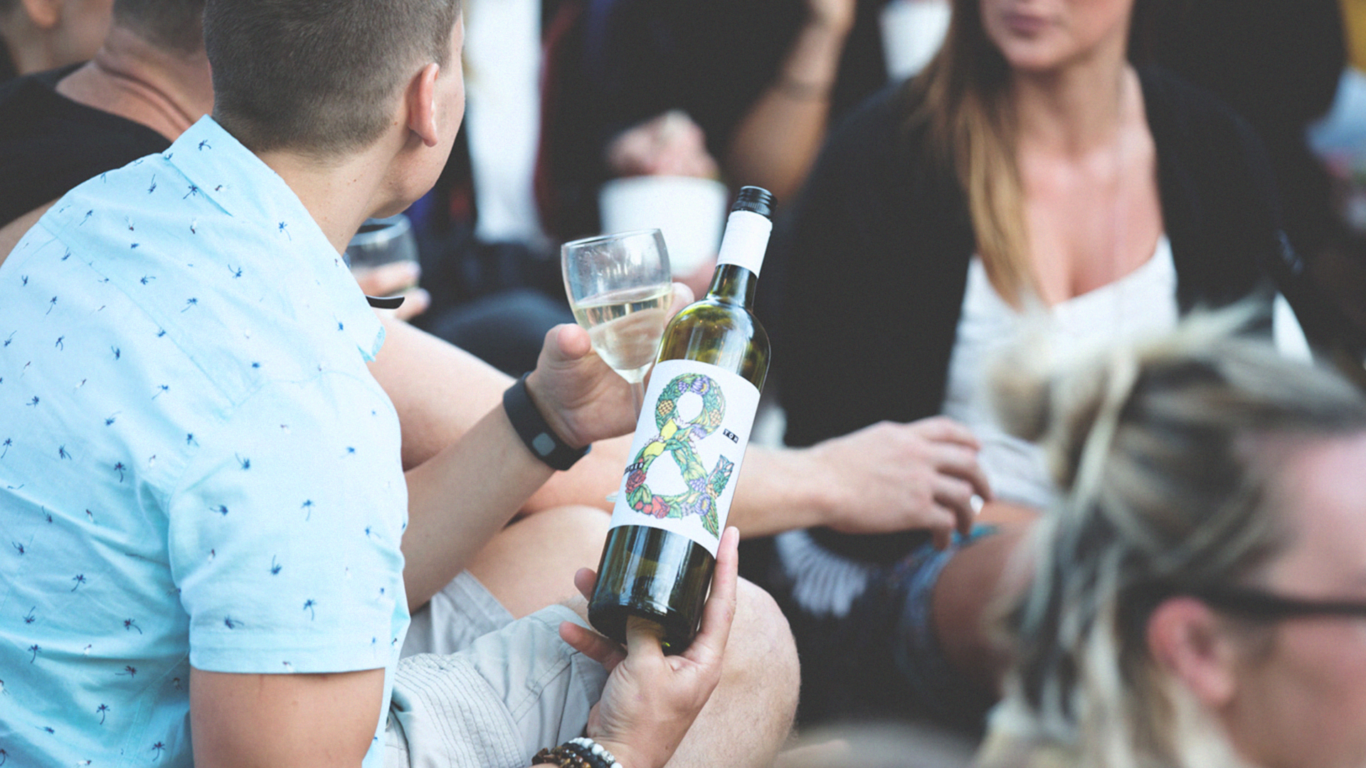 Wine event with people sitting on the ground drinking wine and socialising