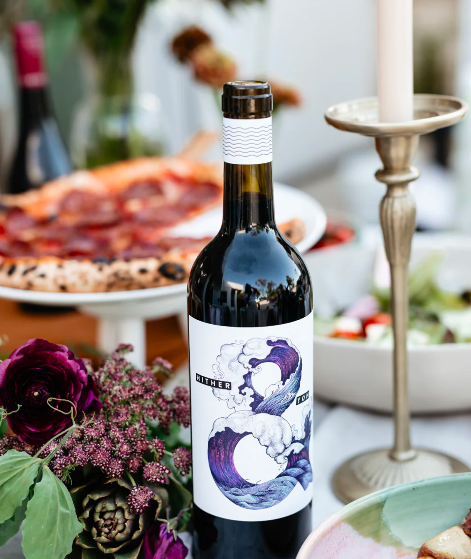 A lunch table setting with food, Hither & Yon wine and a candle stick.