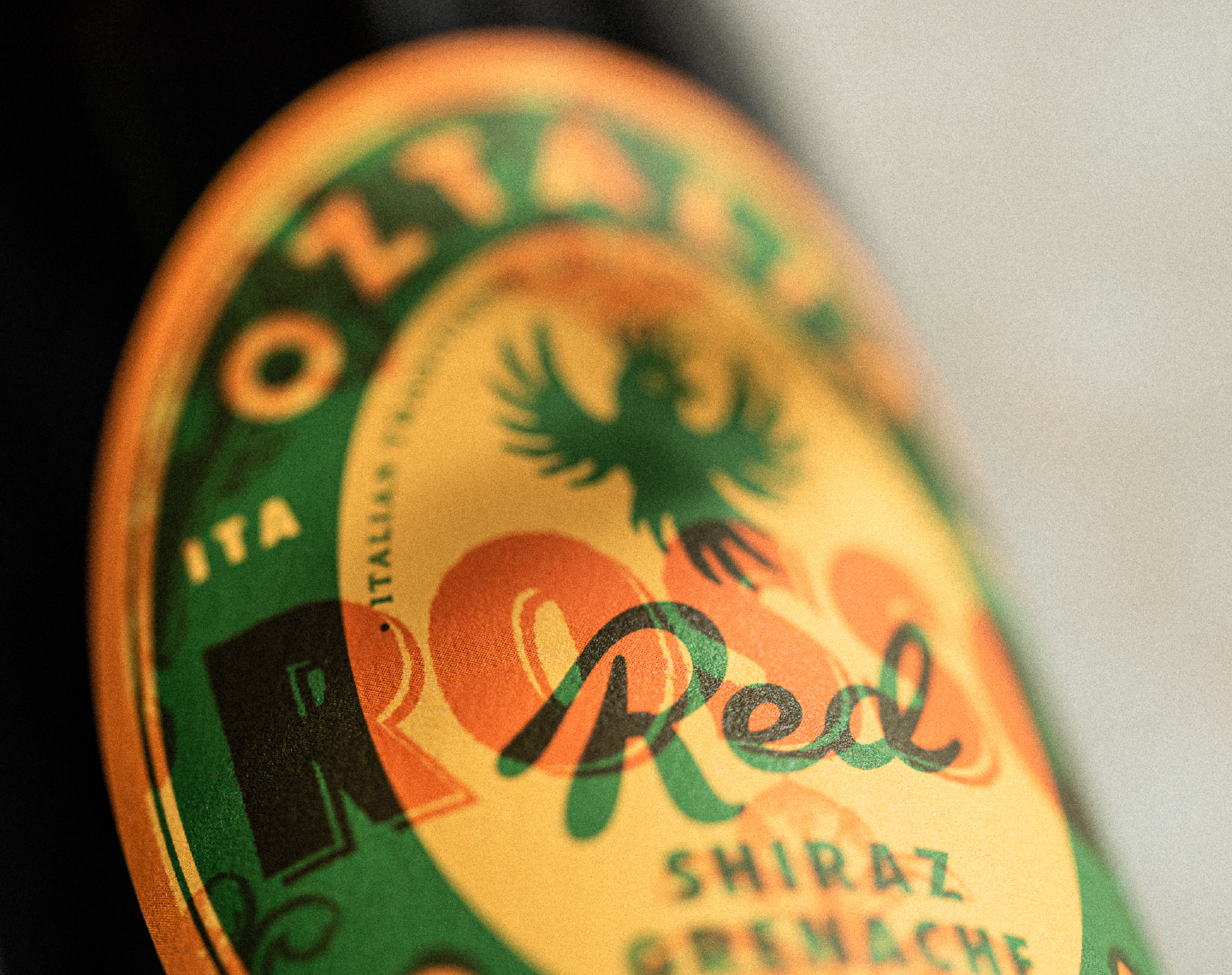 A close up photograph of the Oztalia red wine label featuring a green and red overlay overprint on a yellow background. 