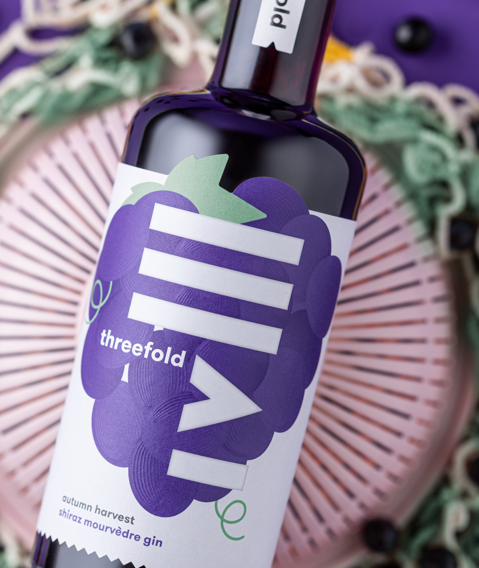 A closeup photograph of the Autumn Harvest Shiraz Mourvèdre gin with a colourful, purple grape label design with a sculptural textured emboss effect.