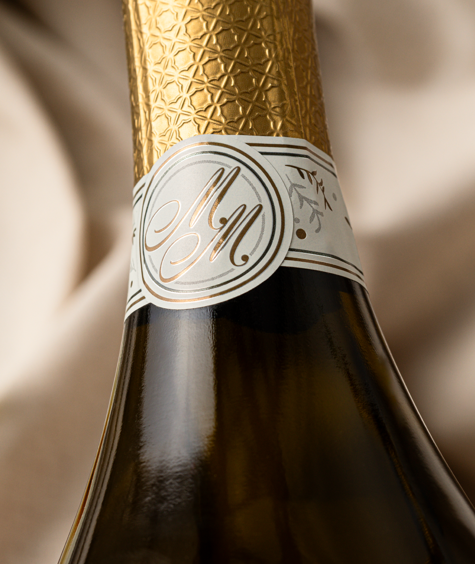 Close up on back of sparkling neck label showing Martha Mae monogram