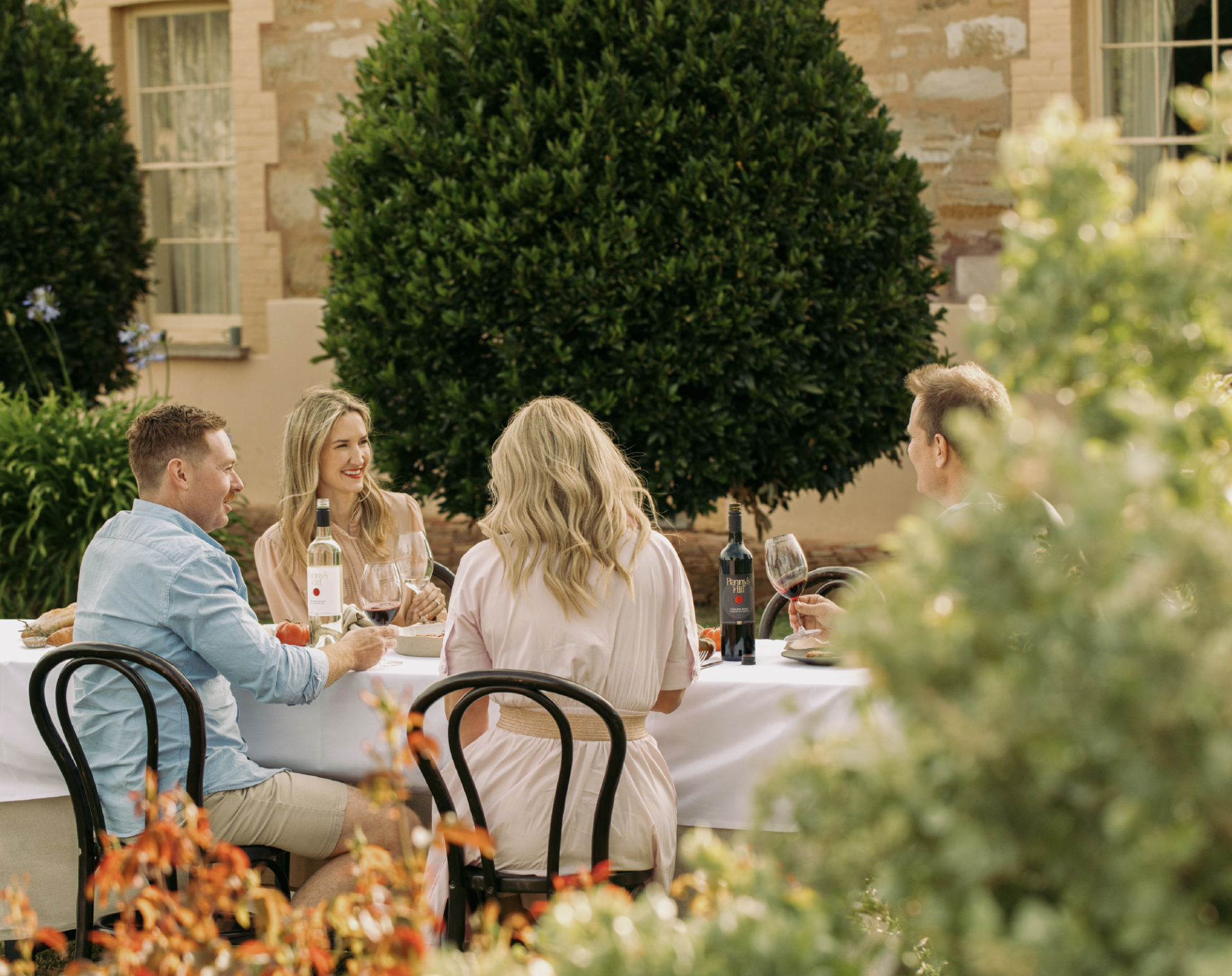 Four people sat at a table sharing wines from Penny's Hilll Homestead range.