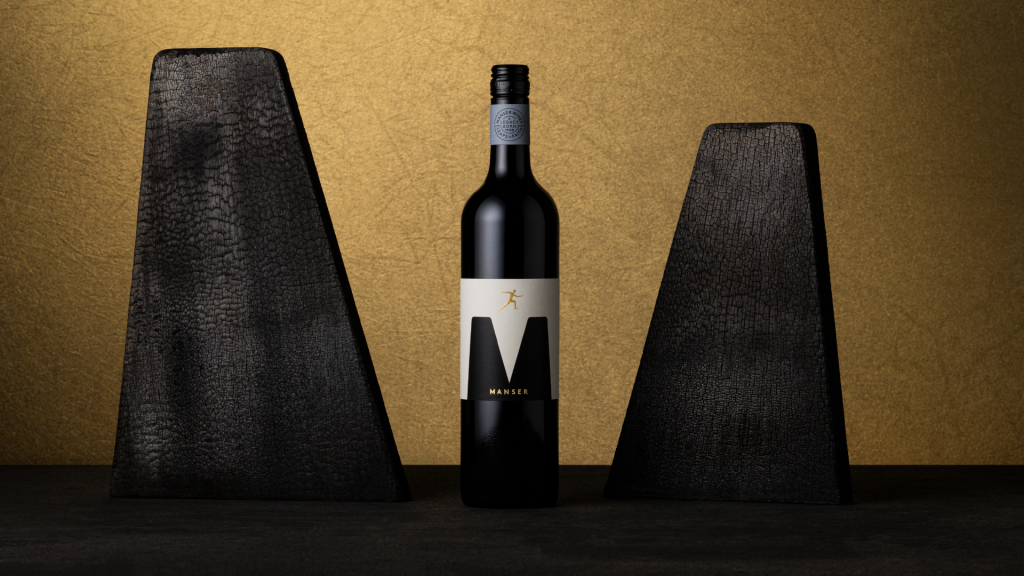 Full bottle image featuring gold sculptural emboss of a leaping figure on a dark premium wine label for the Manser Wines Estate Range, showcasing luxury wine packaging and refined label design.