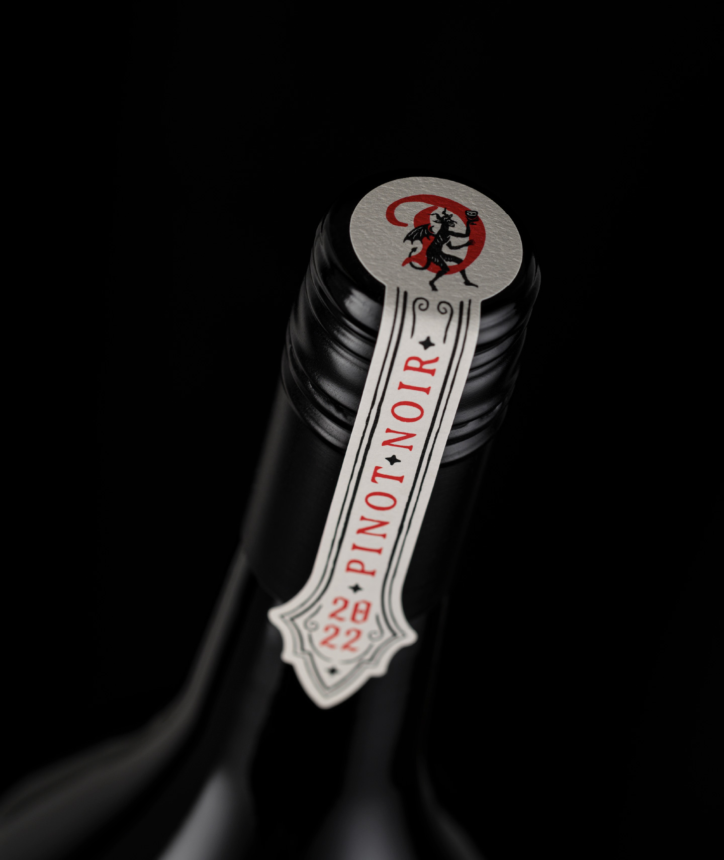 Close-up of the bespoke closure label for The Devil Made Pinot Single Clone, featuring custom typography, ornate bordering, and the signature devil icon on a matte finish.