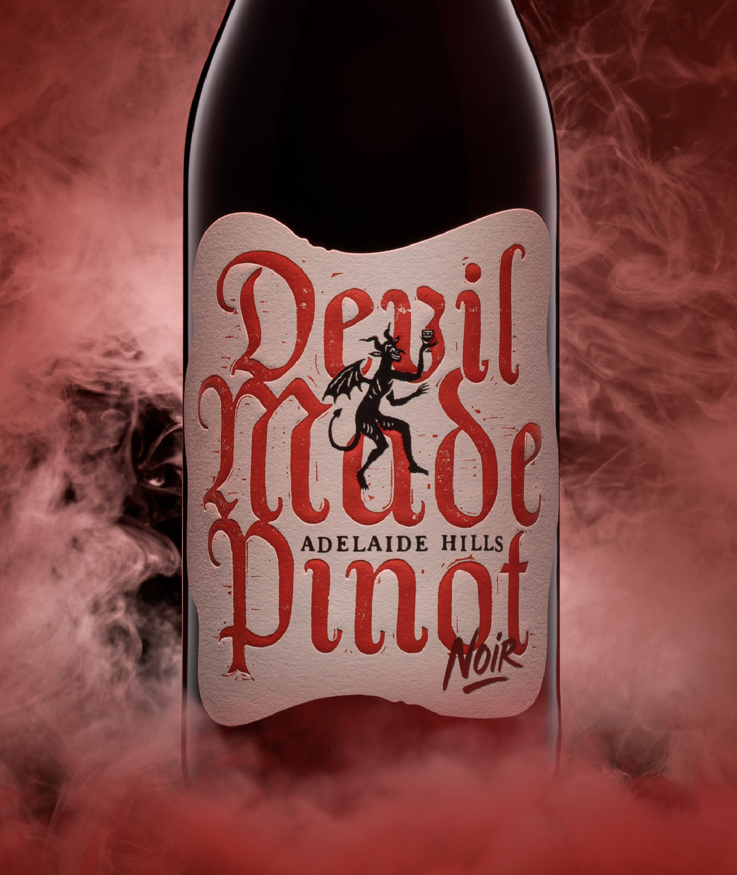 Close-up of the custom wine label design for The Devil Made Pinot, featuring bold red gothic typography, textured paper stock, and intricate devil branding.