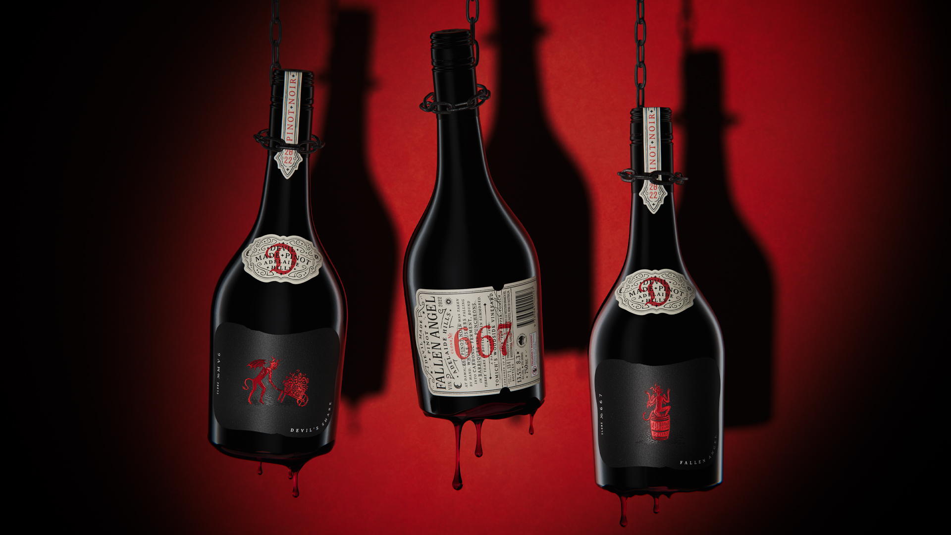 Three bottles of Devil Made Pinot Noir from Adelaide Hills suspended by chains against a red background, featuring "Fallen Angel" and "Devil's Share" labels with red wine dripping from the bases.